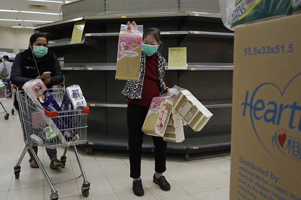 Customers wearing masks, purchase tissue papers in front of the empty shelf in a supermarket in ...