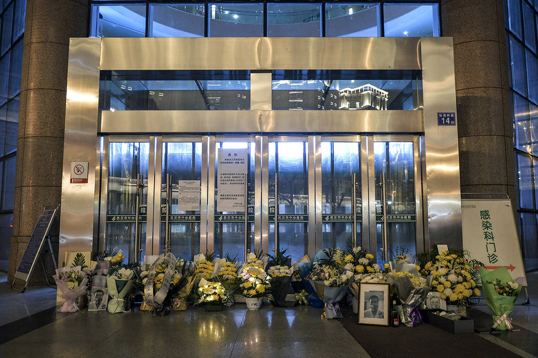 In this Friday, Feb. 7, 2020, photo, flowers are placed near a photo of the late Dr. Li Wenlian ...