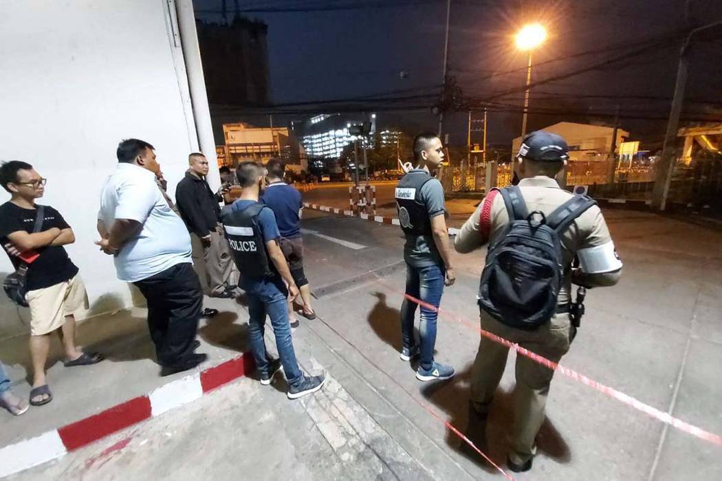 Police and bystanders stand near the scene of a shooting at the Terminal 21 mall, in Korat, Tha ...