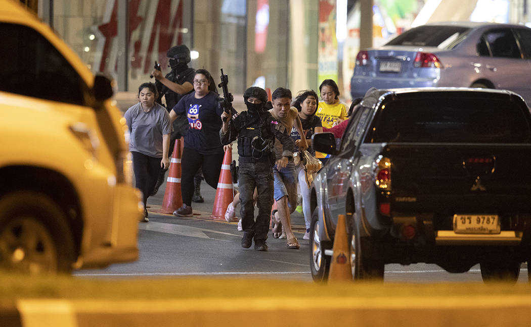 People who were able to get out of Terminal 21 Korat mall, are escorted outside by armed comman ...