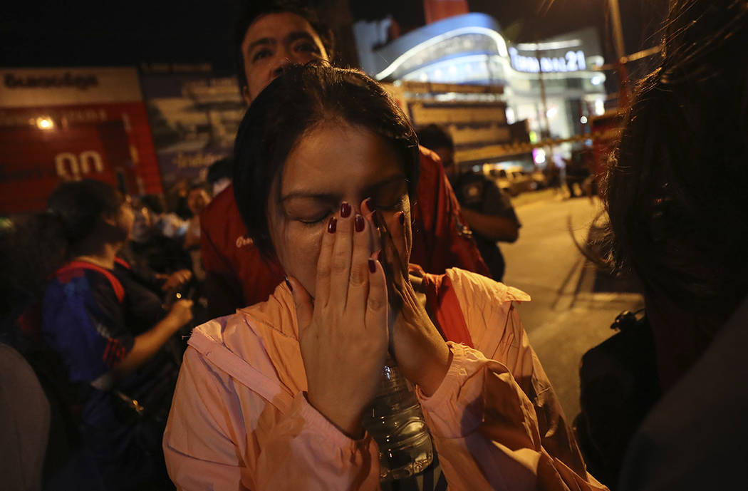 A woman who was able to get out of Terminal 21 Korat mall gestures with her hands on her face i ...