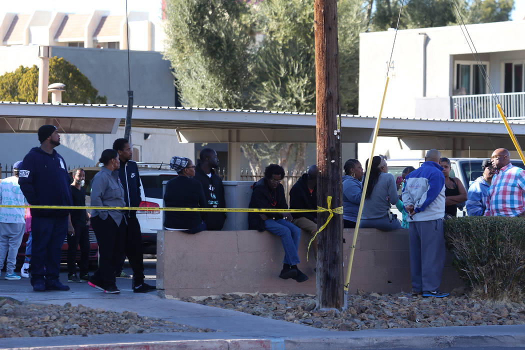 People watch as police investigate a homicide in a shopping center at the intersection of Swens ...