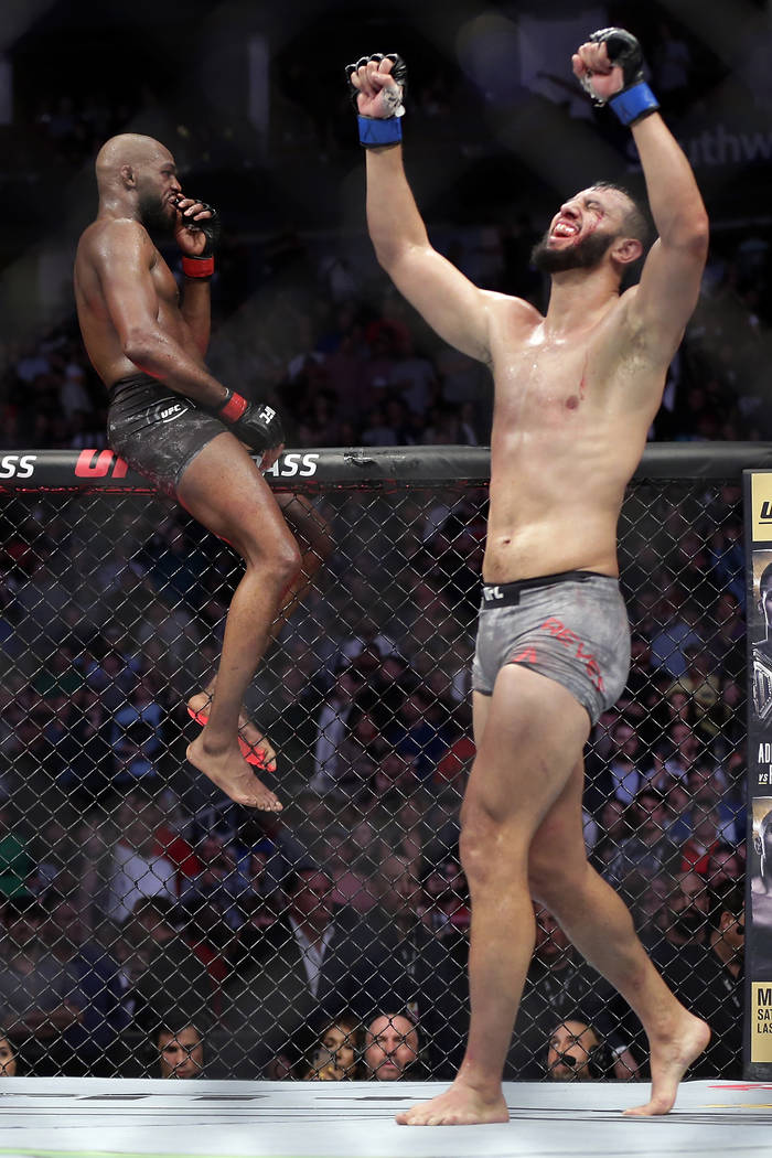 Jon Jones, left, sits on the fence as Dominick Reyes, right, celebrates immediately after their ...