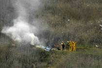 FILE - In this Jan. 26, 2020 file photo firefighters work the scene of a helicopter crash where ...