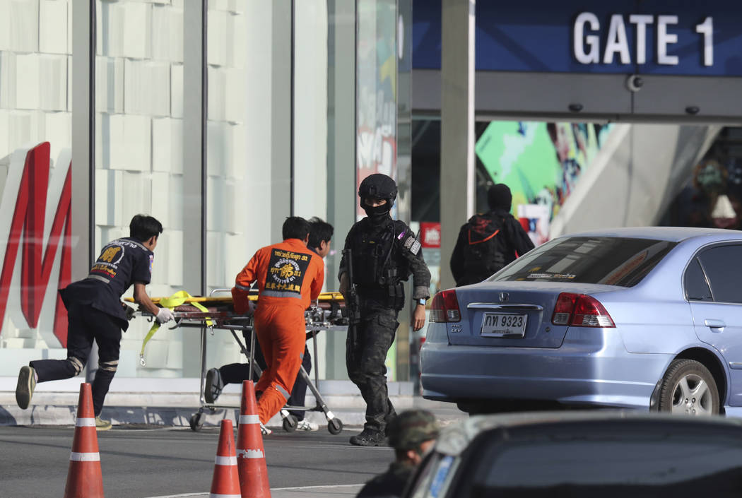 Medics carry a stretcher towards Terminal 21 Korat mall as commando soldiers work the scene of ...