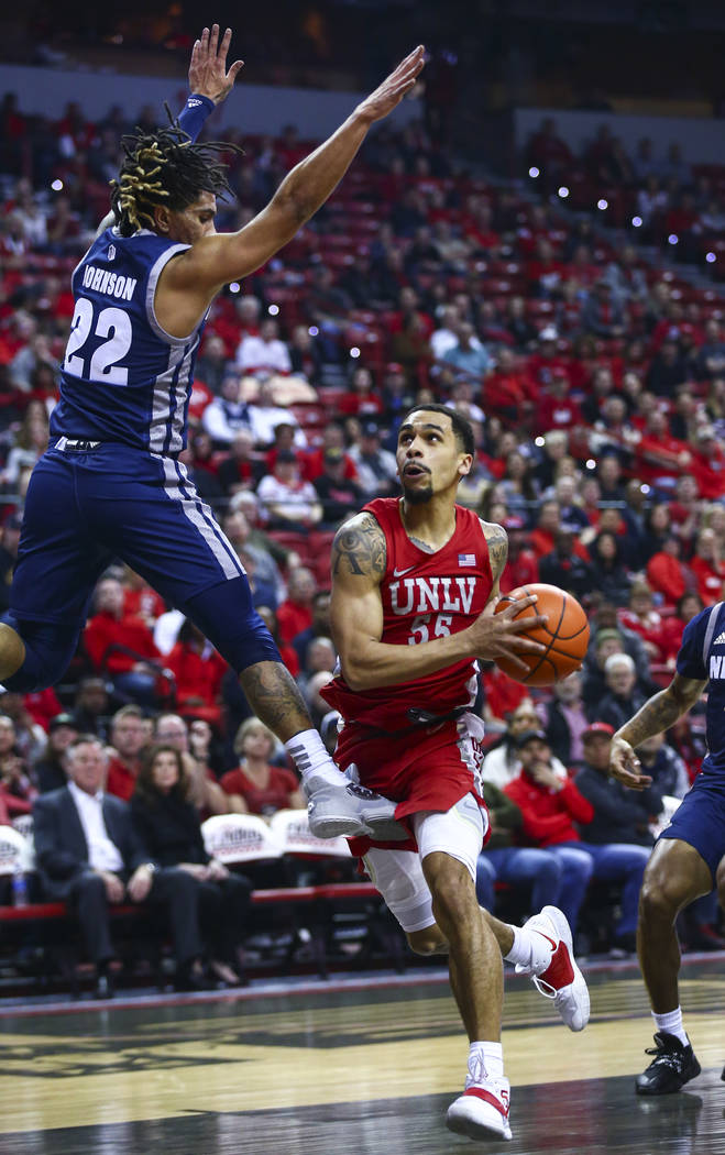 UNLV's Elijah Mitrou-Long (55) drives to the basket as UNR's Jazz Johnson (22) defends during t ...