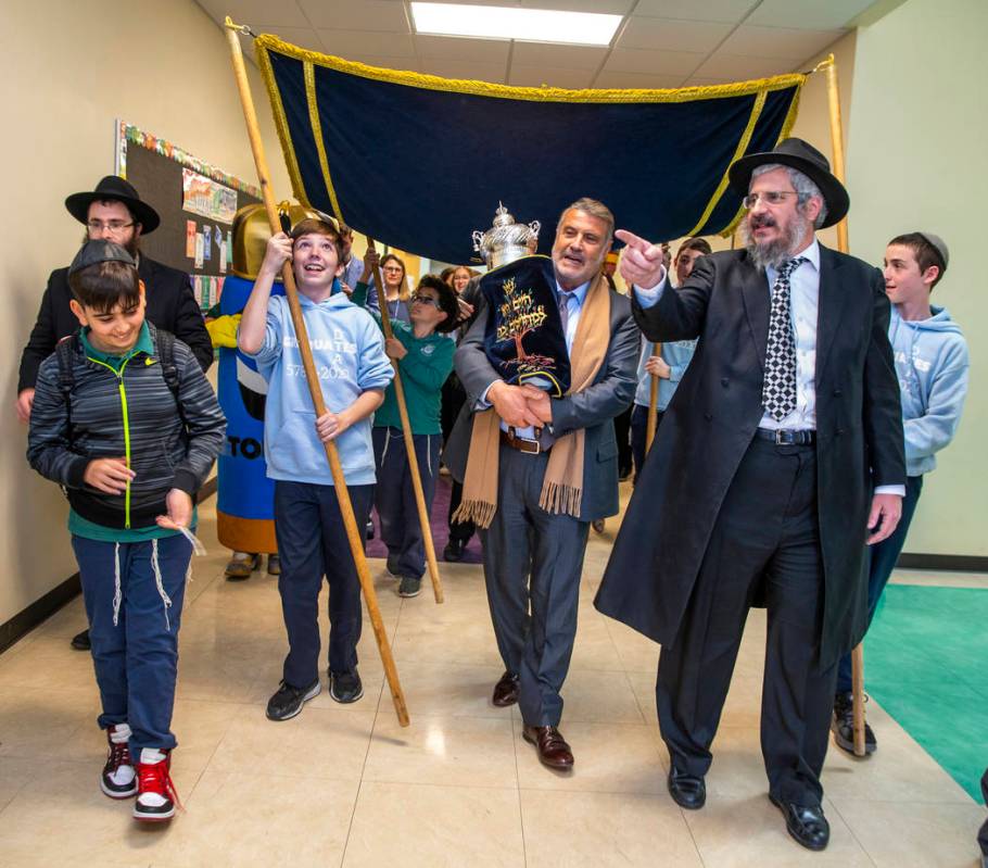 Sonny Kahn, center, carries a newly inscribed Torah beside Rabbi Shea Harlig, right, as they pr ...