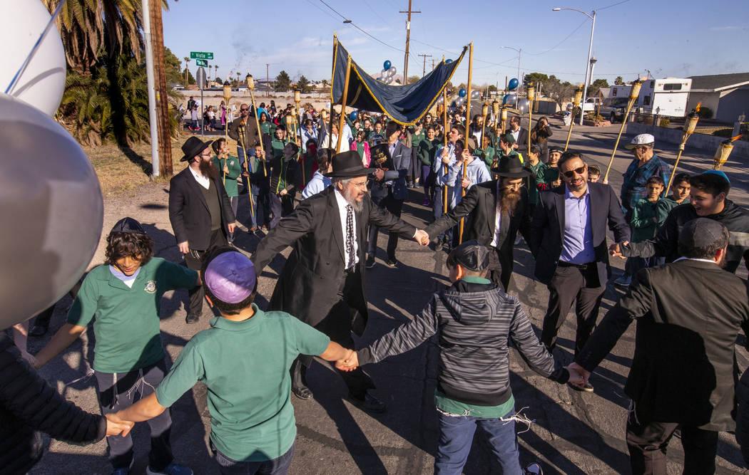 Chabad of Southern Nevada members march and dance while carrying their new Torah about the neig ...