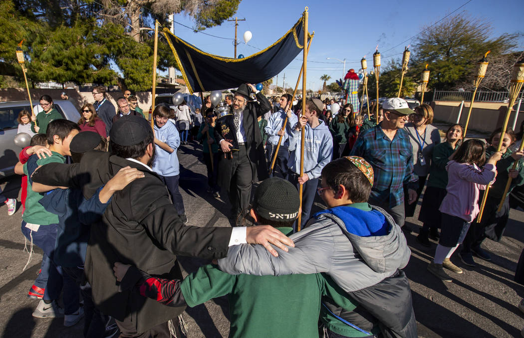 Chabad of Southern Nevada members march and dance while carrying their new Torah about the neig ...