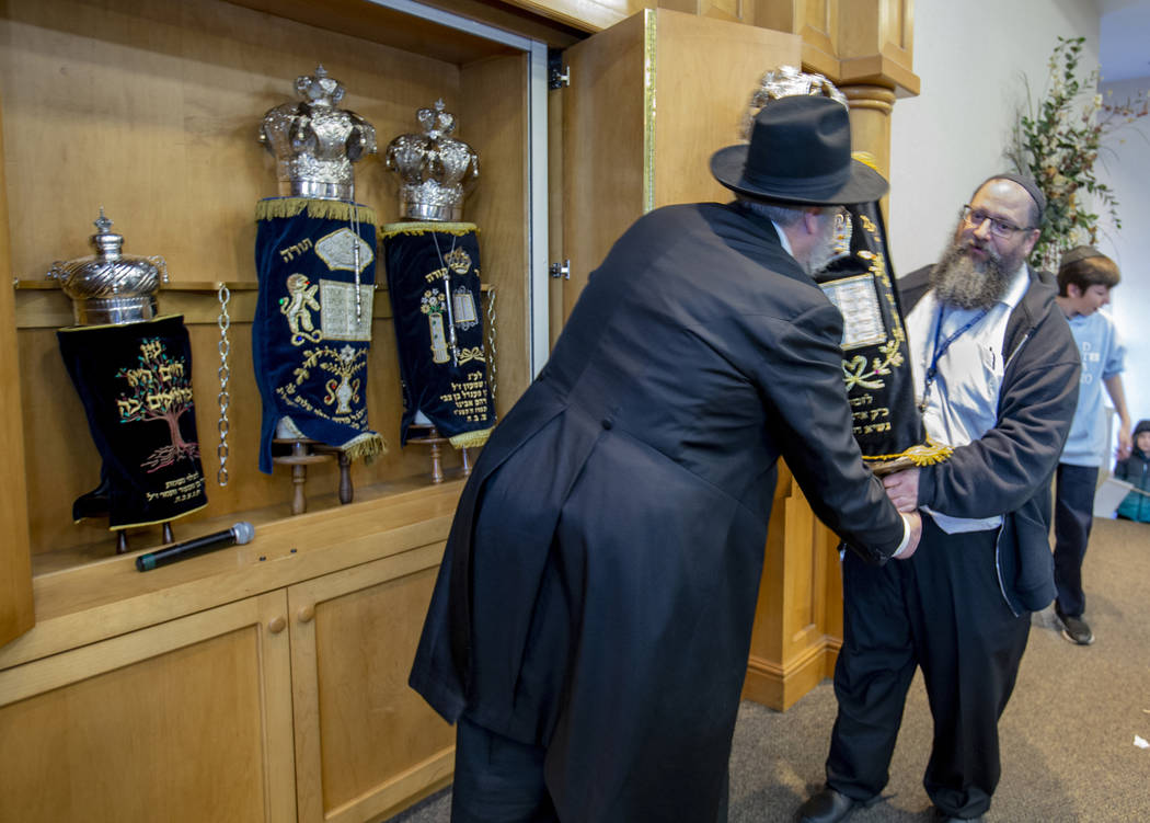 Rabbi Shea Harlig, left, puts away their new Torah joining the three existing ones in their syn ...