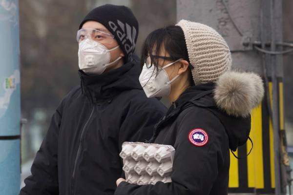 Residents wearing masks wait at a traffic light in Beijing, China Thursday, Feb. 13, 2020. Chin ...