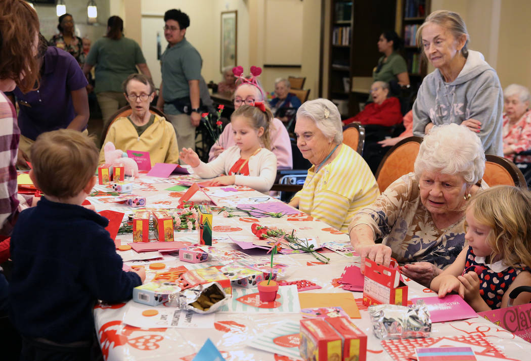 Katerina Smith, 4, right, and Elise Adoor, 5, center, make a Valentine's Day themed craft with ...