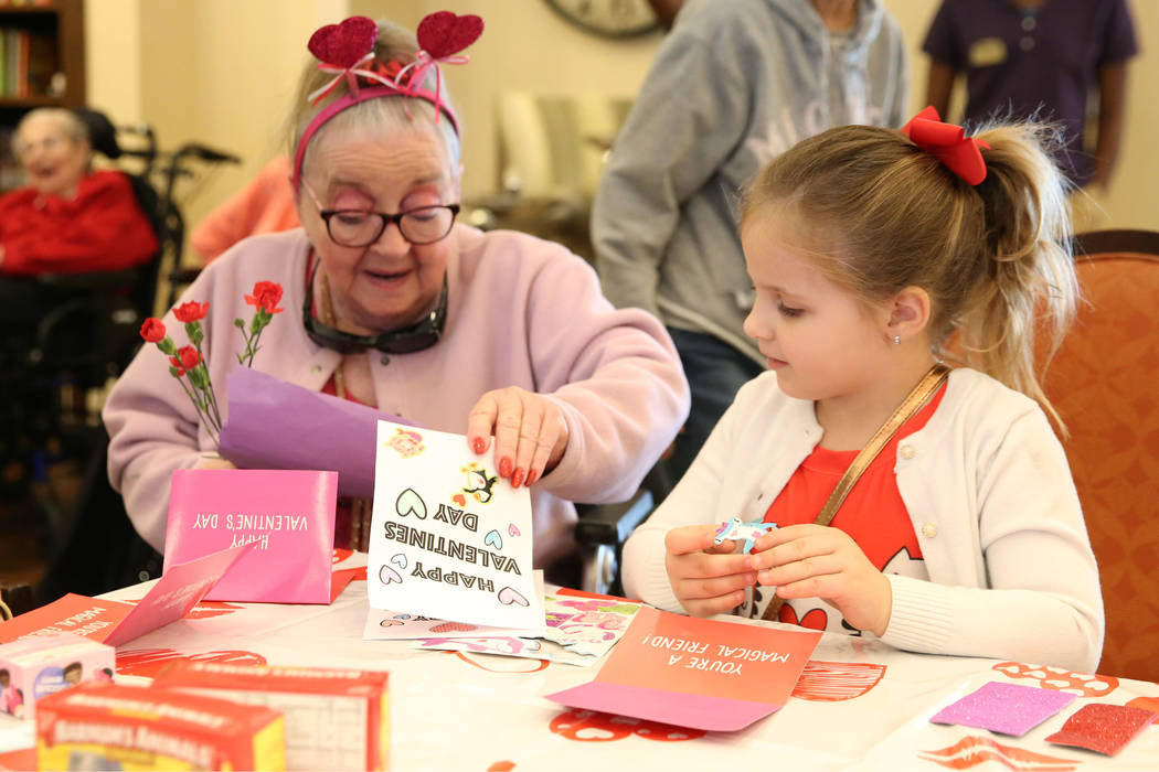Elise Adoor, 5, center, makes a Valentine's Day themed craft with Barbara Wokosky, 85, at Poet' ...