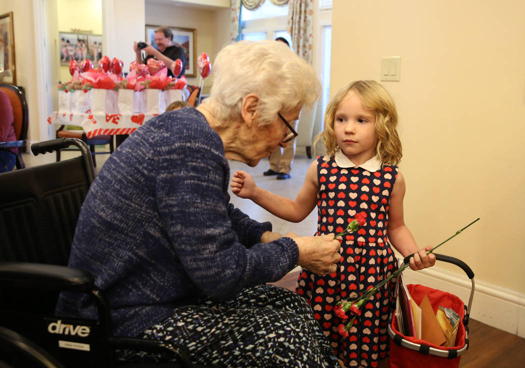 Katerina Smith, 4, hands out Valentine's flowers to Erika Totera at Poet's Walk, a memory care ...