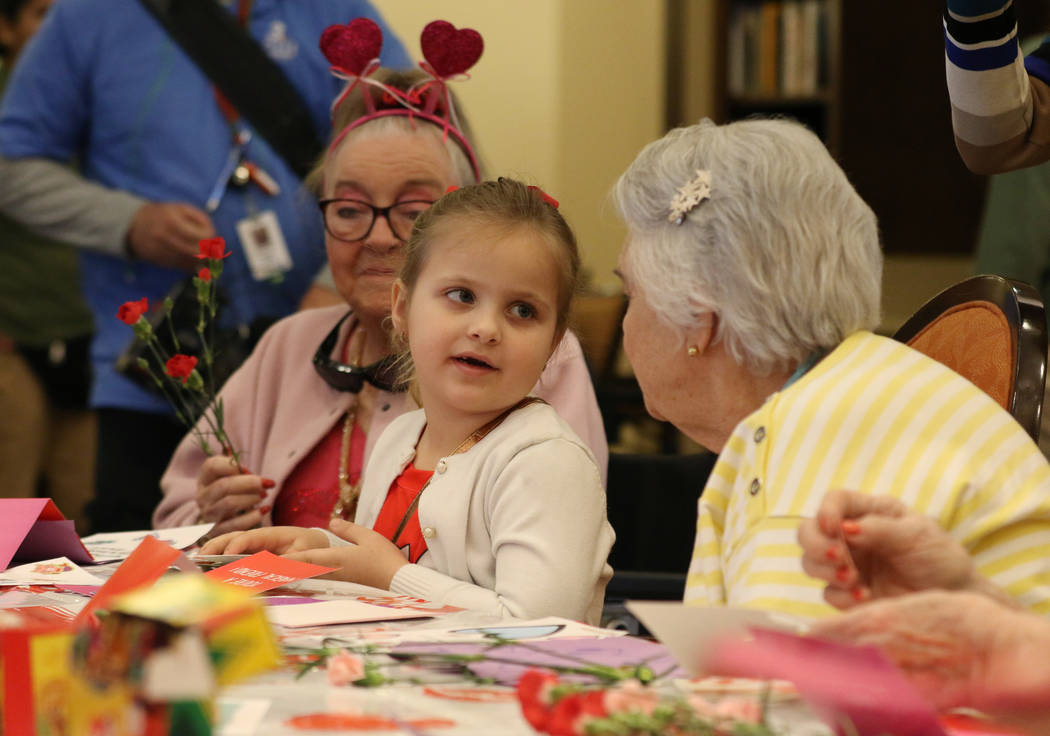 Elise Adoor, 5, center, makes a Valentine's Day themed craft with Barbara Wokosky, left, and Ma ...