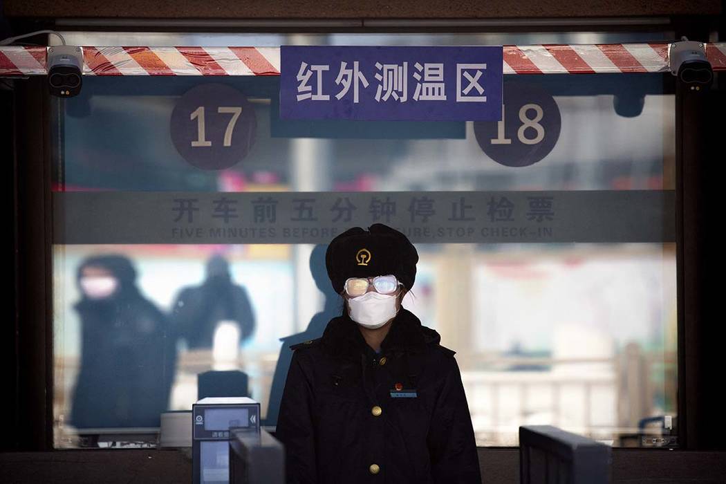 A station worker wears a face mask and goggles as she waits to check passengers' tickets at the ...