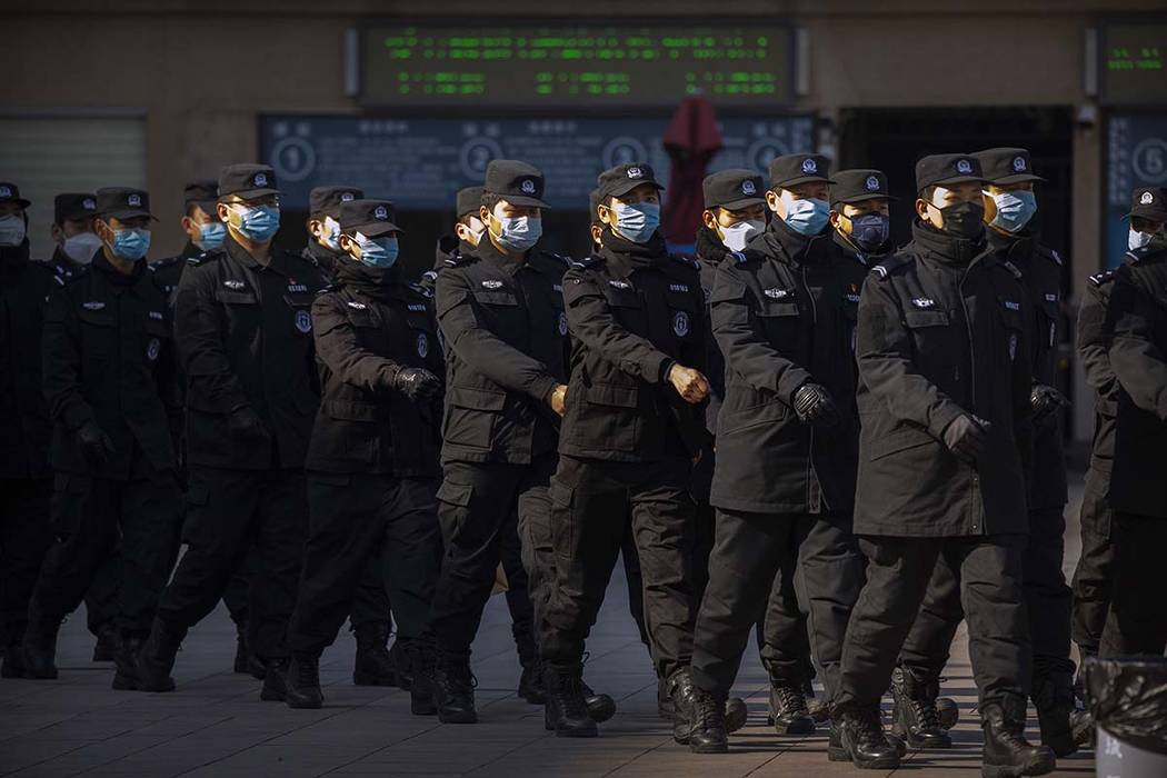 Policemen wear face masks as they march in formation outside the Beijing Railway Station in Bei ...