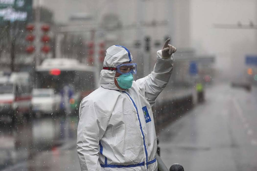 A worker wearing a protective suit gestures to a driver outside a tumor hospital newly designat ...