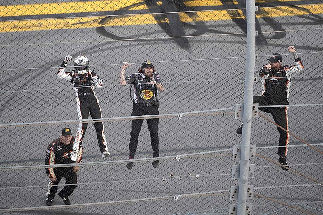 Noah Gragson, left, and crew members celebrate by climbing onto the grandstands safety fence af ...