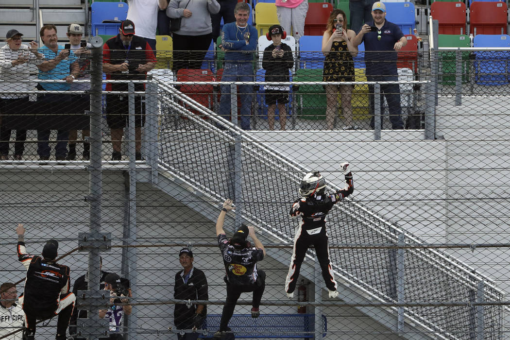 Noah Gragson, lower right, climbs the catch fence as he celebrates his win in the NASCAR Xfinit ...