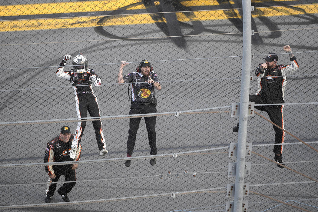 Noah Gragson, left, and crew members celebrate by climbing onto the grandstands safety fence af ...