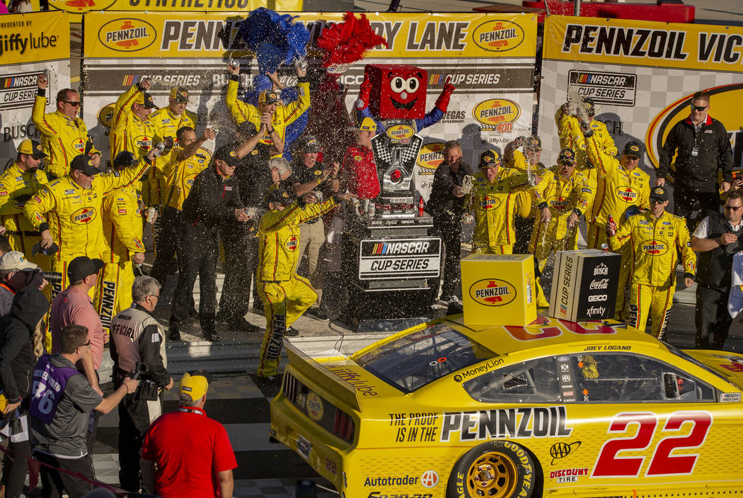Crew members spray Joey Logano (22) with beer as he exits the car to celebrate in the winner's ...