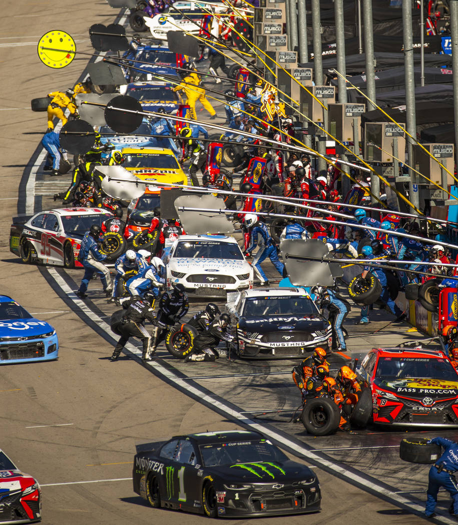Crews scramble about during the first pit in the Pennzoil 400 presented by Jiffy Lube, a NASCAR ...