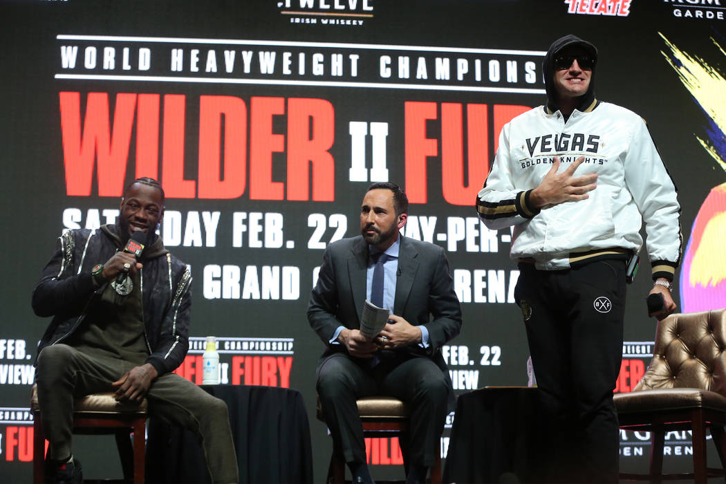 Deontay Wilder, left, and Tyson Fury, participate in a press conference as moderator sportscast ...