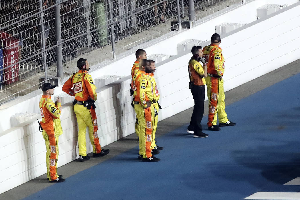 Ryan Newman's crew stands near a wall on pit road as they are kept back from rescue workers tha ...