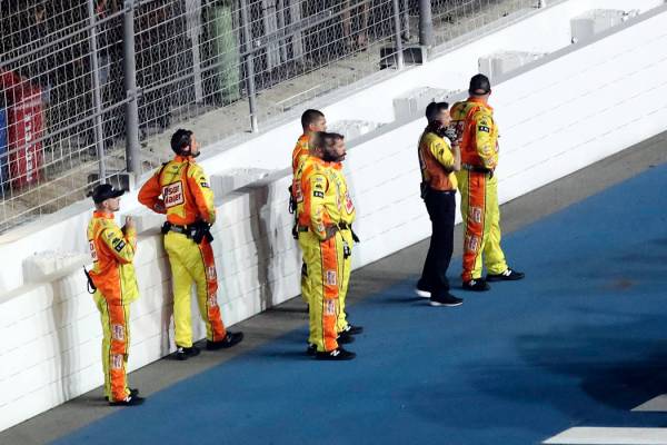 Ryan Newman's crew stands near a wall on pit road as they are kept back from rescue workers tha ...
