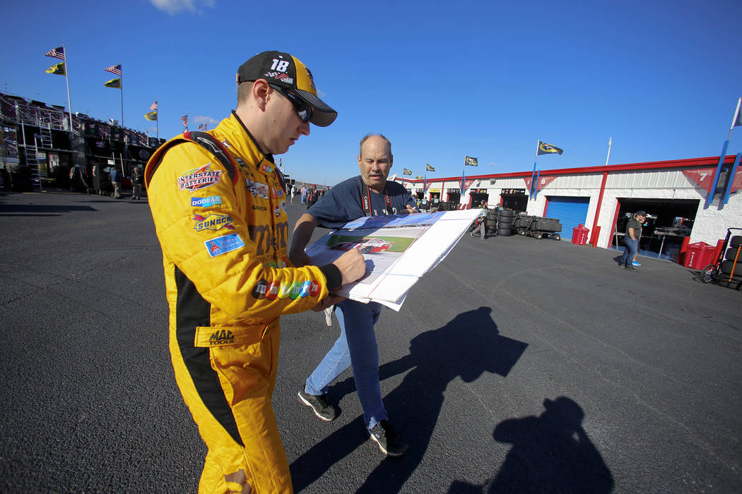 Kyle Busch signs an autograph for a fan as he walks back to the garage area during practice for ...