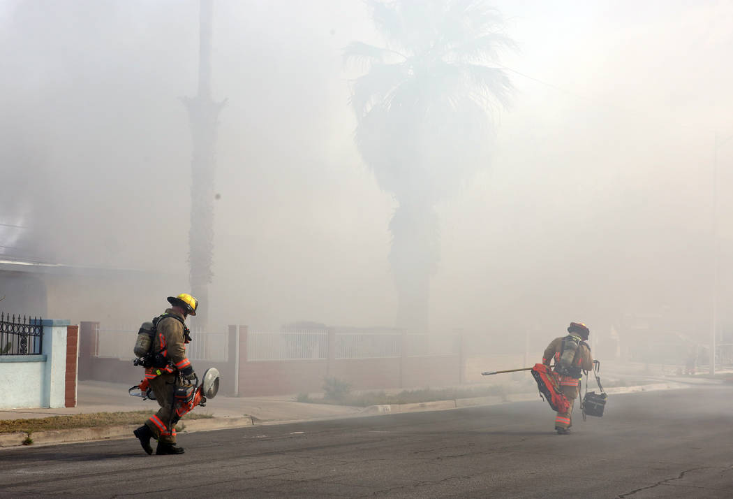 Heavy smoke is seen as Las Vegas firefighters prepare to battle a house fire at 2417 Howard Dri ...