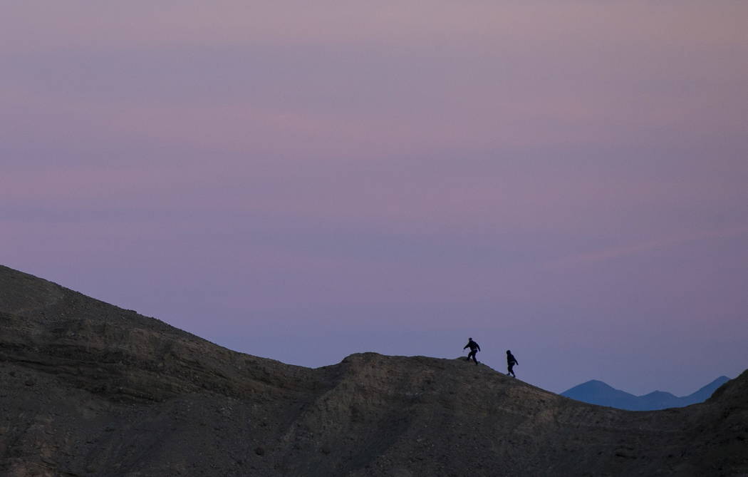 People, as seen looking east from Zabriskie Point, make their way up a ridge before sunset in D ...