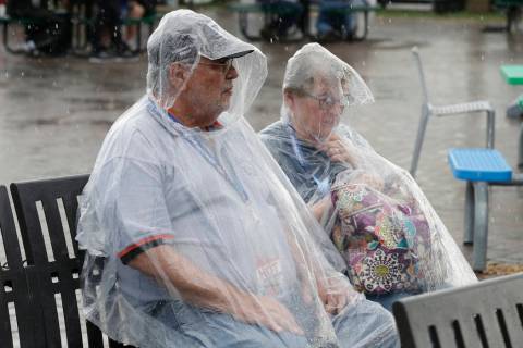Race fans sit on a bench in the Fan Zone after rain stopped the NASCAR Daytona 500 auto race at ...