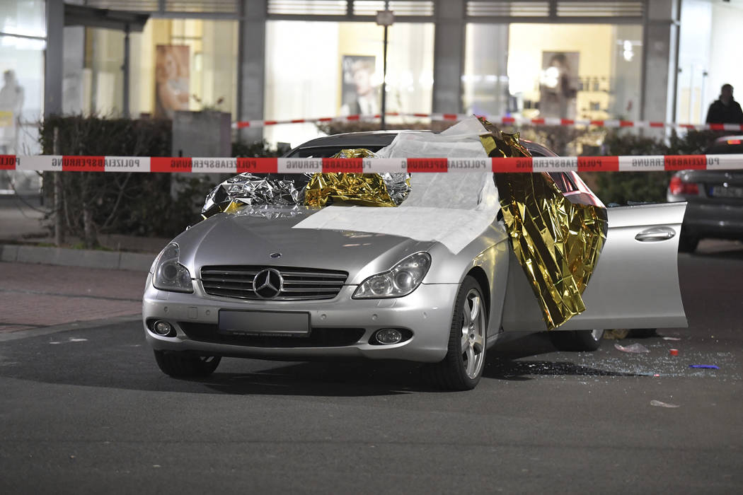A car that was damaged in a shooting is covered in thermo foil is parked in front of a bar at t ...