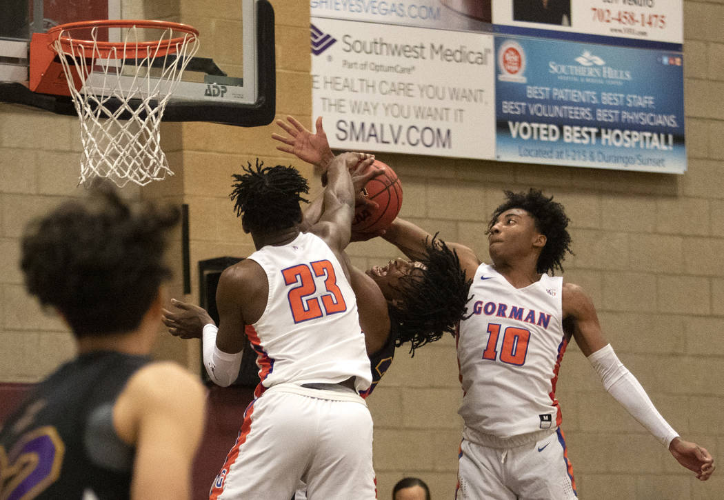 Durango's Anthony Hunter (21) misses a shot as Bishop Gorman's Zaon Collins (10) and Mwani Wilk ...