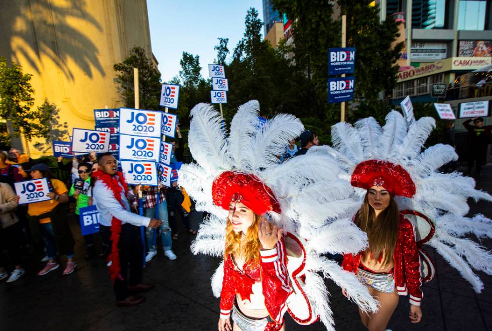 Showgirls walk past supporters of Democratic presidential candidate Joe Biden ahead of the Demo ...