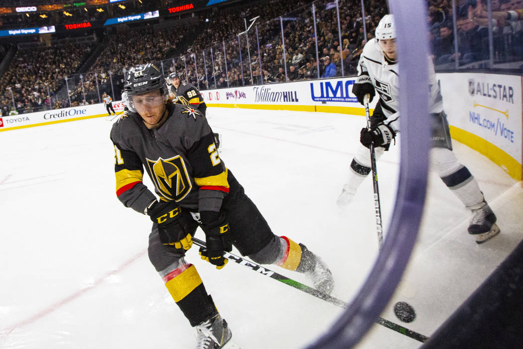 Golden Knights' Cody Eakin (21) moves the puck in front of Los Angeles Kings' Ben Hutton (15) d ...