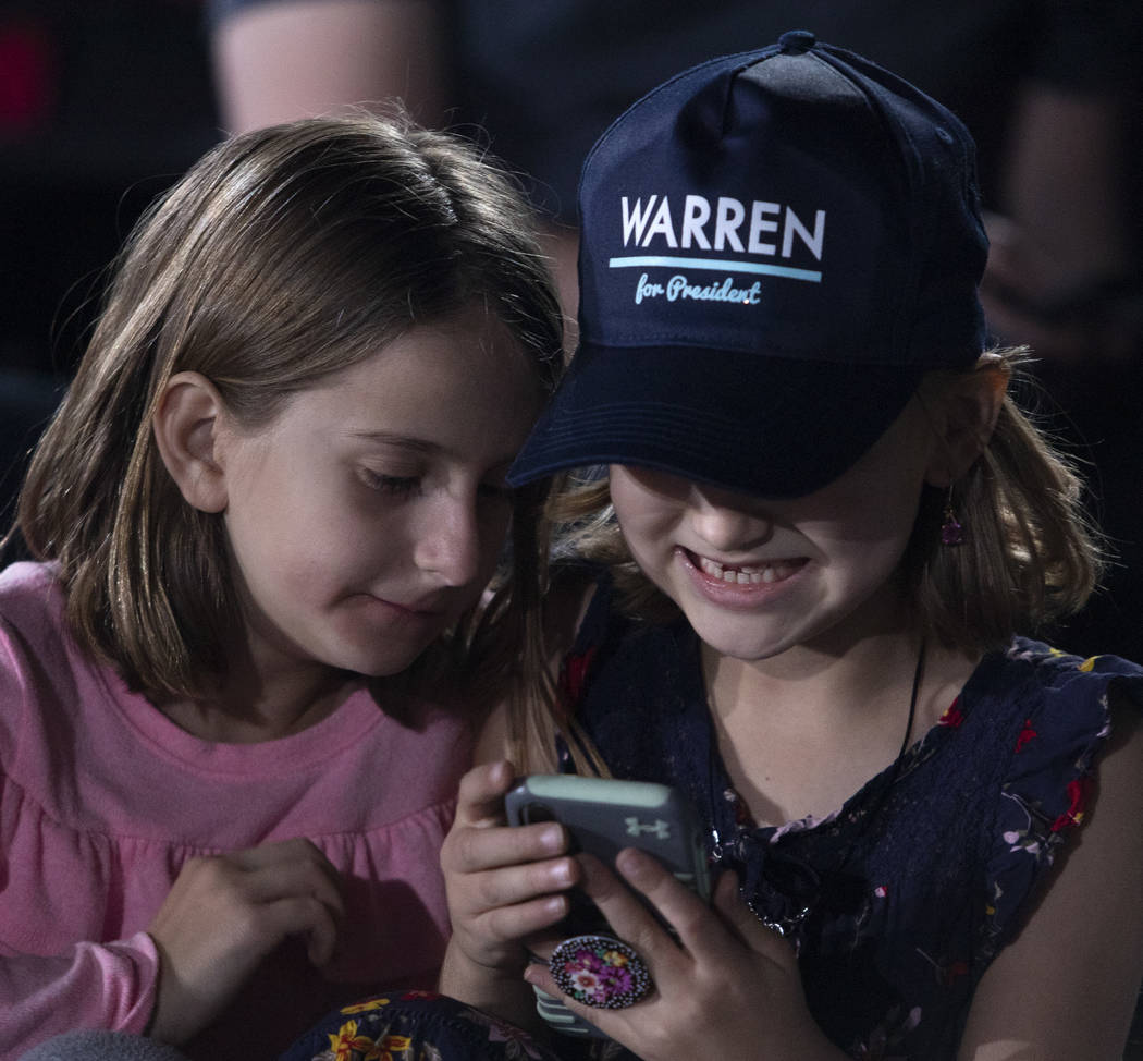 Haylie Bakst, 7, left, and her friend Mia Voos, 7, giggle at a cell phone before Sen. Elizabeth ...