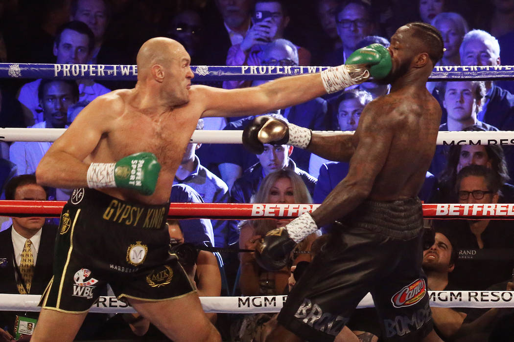 Tyson Fury, left, connects with a jab against Deontay Wilder in the first round during their WB ...
