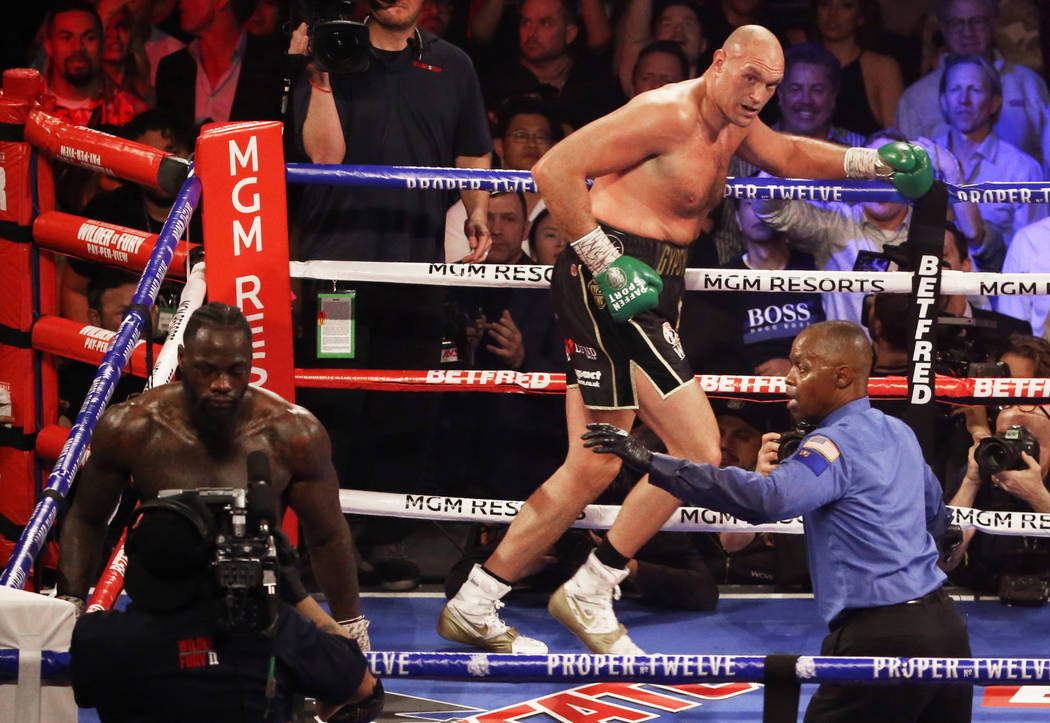 Tyson Fury, top/right, runs to his corner after knocking down Deontay Wilder in the fifth round ...