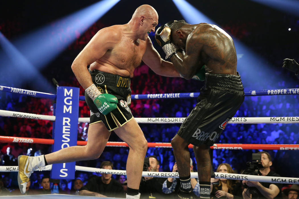 Tyson Fury, left, connects a punch to knock down Deontay Wilder in round 5 of the WBC world hea ...