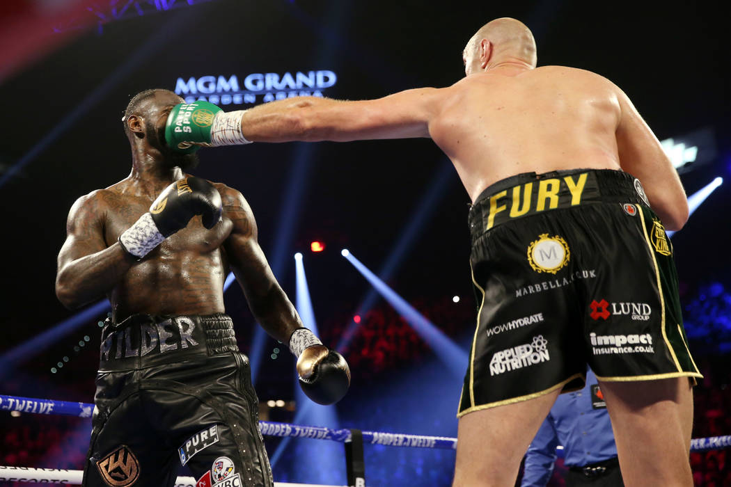 Tyson Fury, right, connects a punch against Deontay Wilder in round 2 of the WBC world heavywei ...