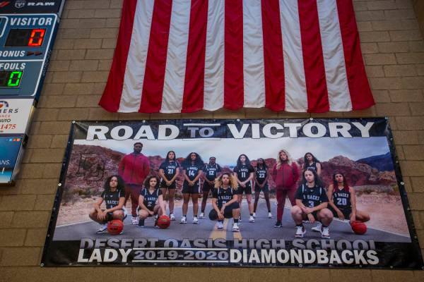 A banner hanging in the gym features the players and coaches of the Desert Oasis girl's basketb ...