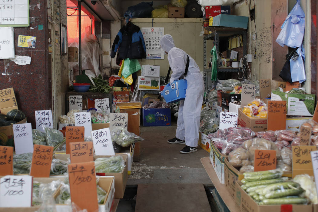 A worker wearing a protective suit sprays disinfectant as a precaution against the COVID-19 at ...