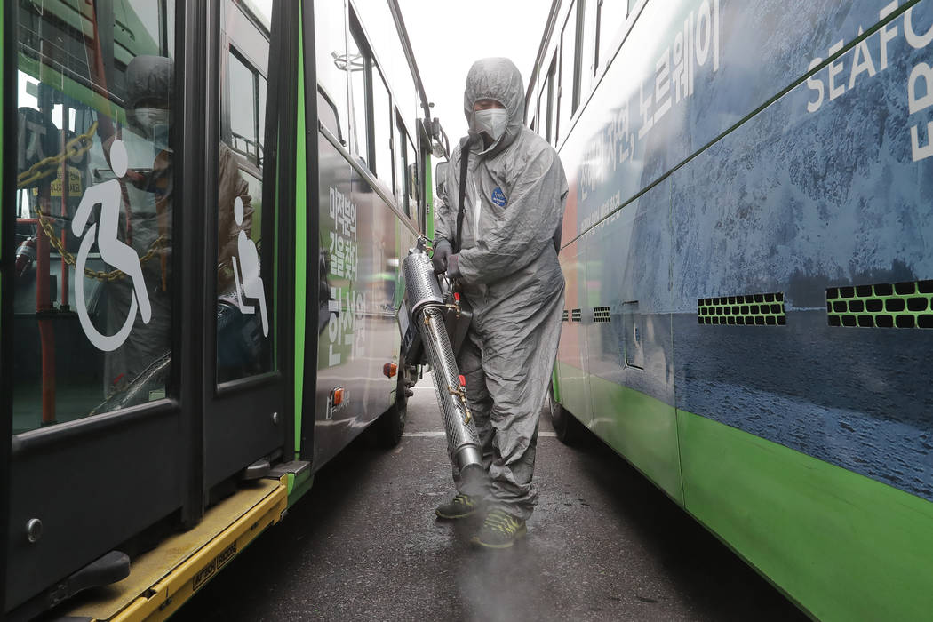 A worker wearing a protective suit sprays disinfectant as a precaution against the coronavirus ...