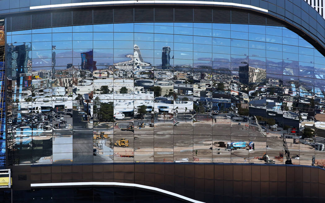 Nearby businesses and casino properties are reflected on the facade of Allegiant Stadium as con ...