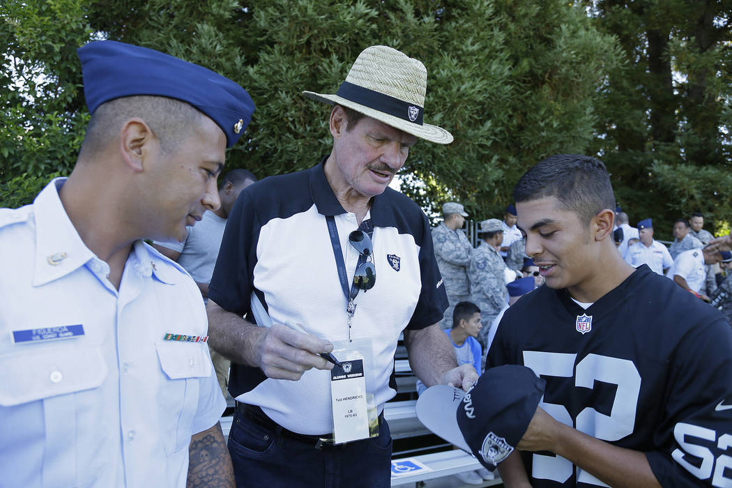 Former Oakland Raiders linebacker Ted Hendricks, center, signs autographs during practice at th ...