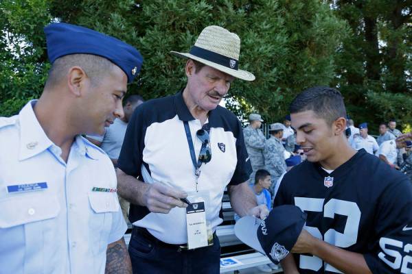 Former Oakland Raiders linebacker Ted Hendricks, center, signs autographs during practice at th ...