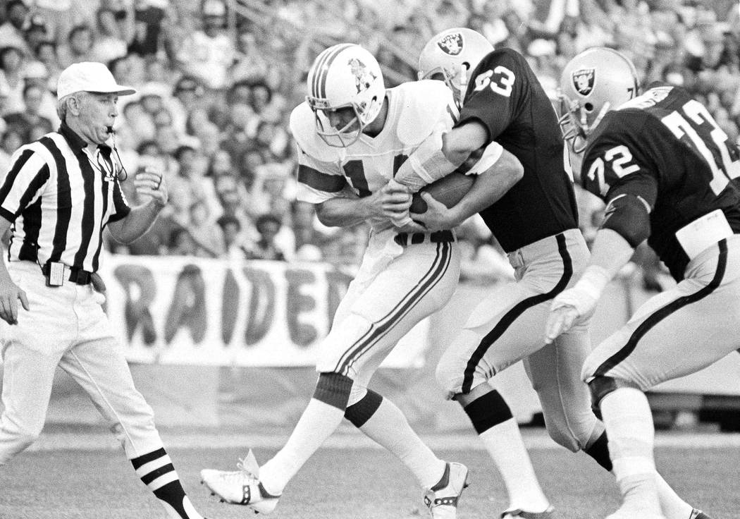 Raiders Ted Hendricks (83) wraps his arms around New England Patriots quarterback Steve Grogan ...